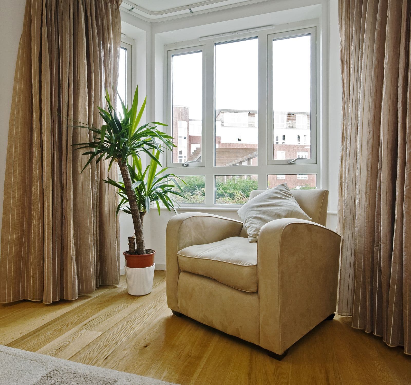 An armchair sits by casement windows in a living room.