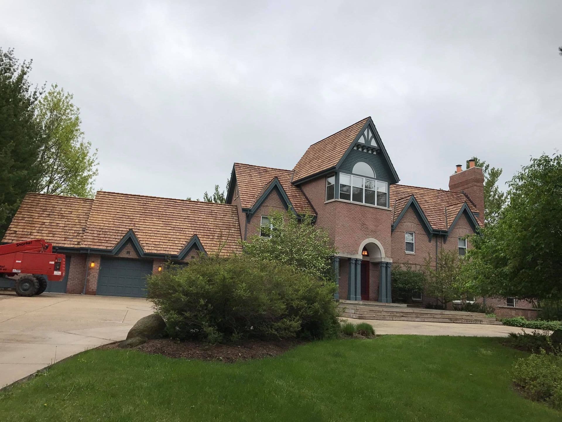 A large brick house with new shake roofing.